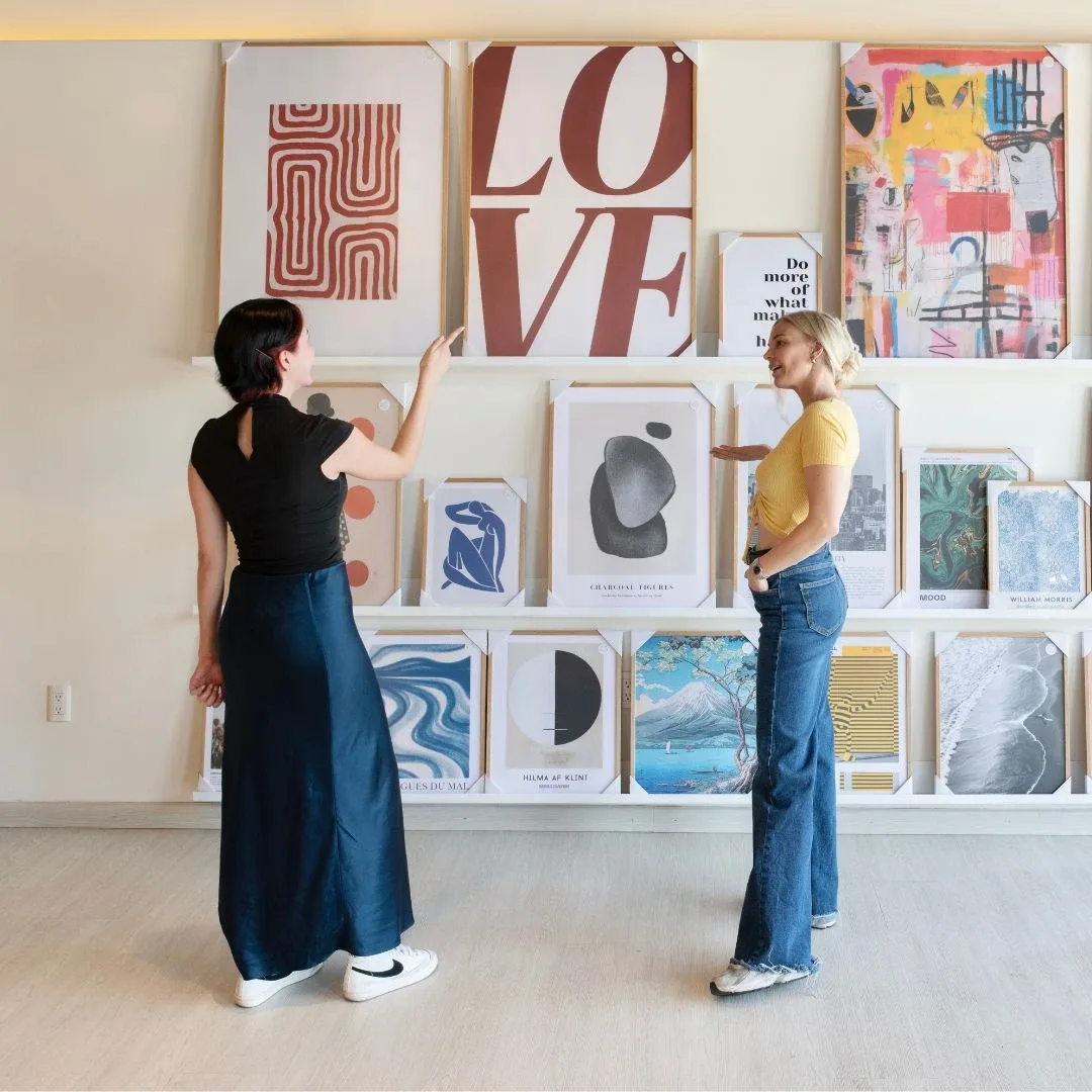 Dos personas eligiendo arte en el showroom de Studio Malek en Guadalajara, rodeadas de cuadros a color